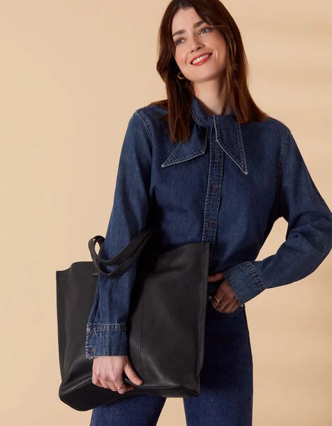 A model holding a large black handbag