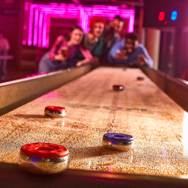 A close up of a shuffleboard with people in the background