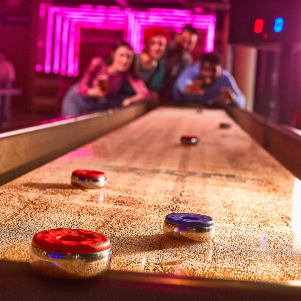 Group of people playing shuffleboard at Boom Battle Bar