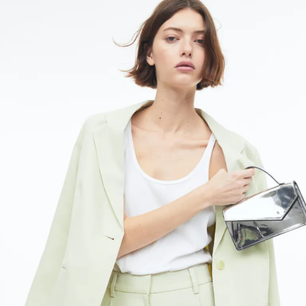 A model wears a green pastel suit with a silver handbag