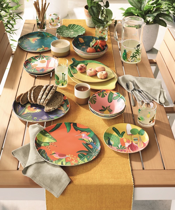 A table with colourful plastic crockery and picnic food.