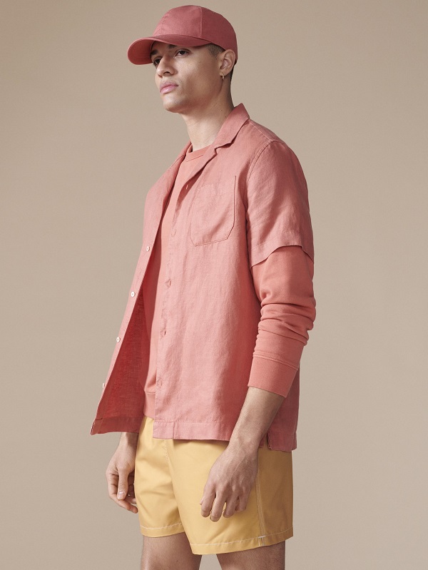 A model wearing all peach clothing including a shirt, shorts and a cap
