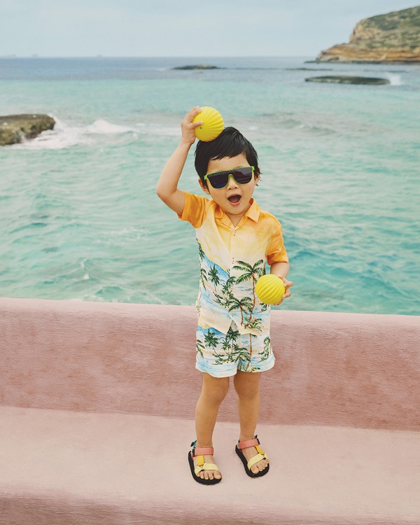 A kid wearing hawaiian shirt and sandals